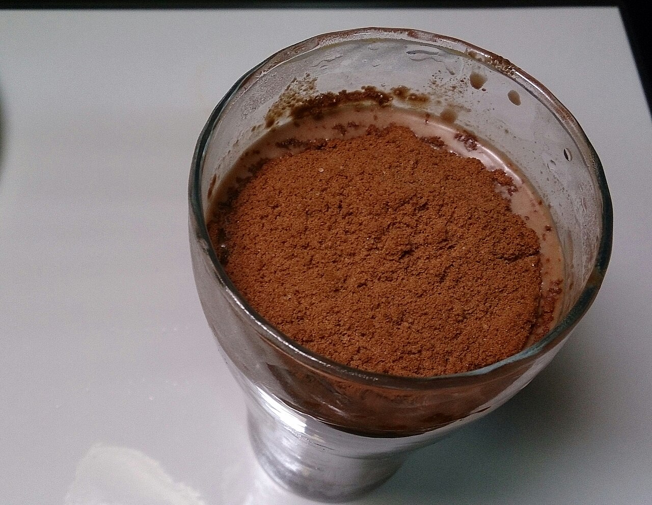 Glass of Milo Dinosaur with a heap of Milo powder on top