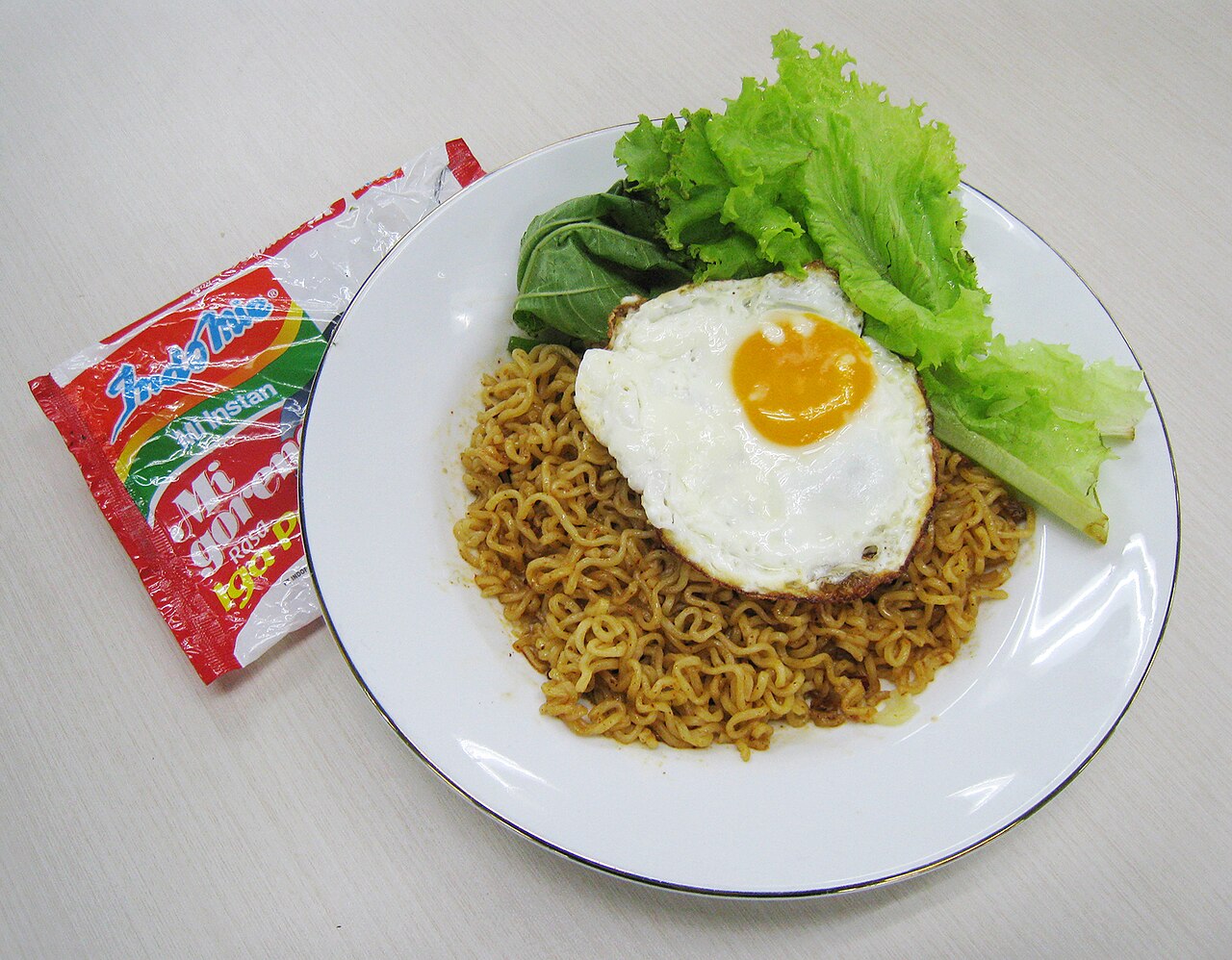 A plate of Indomie Mie Goreng beside its packet