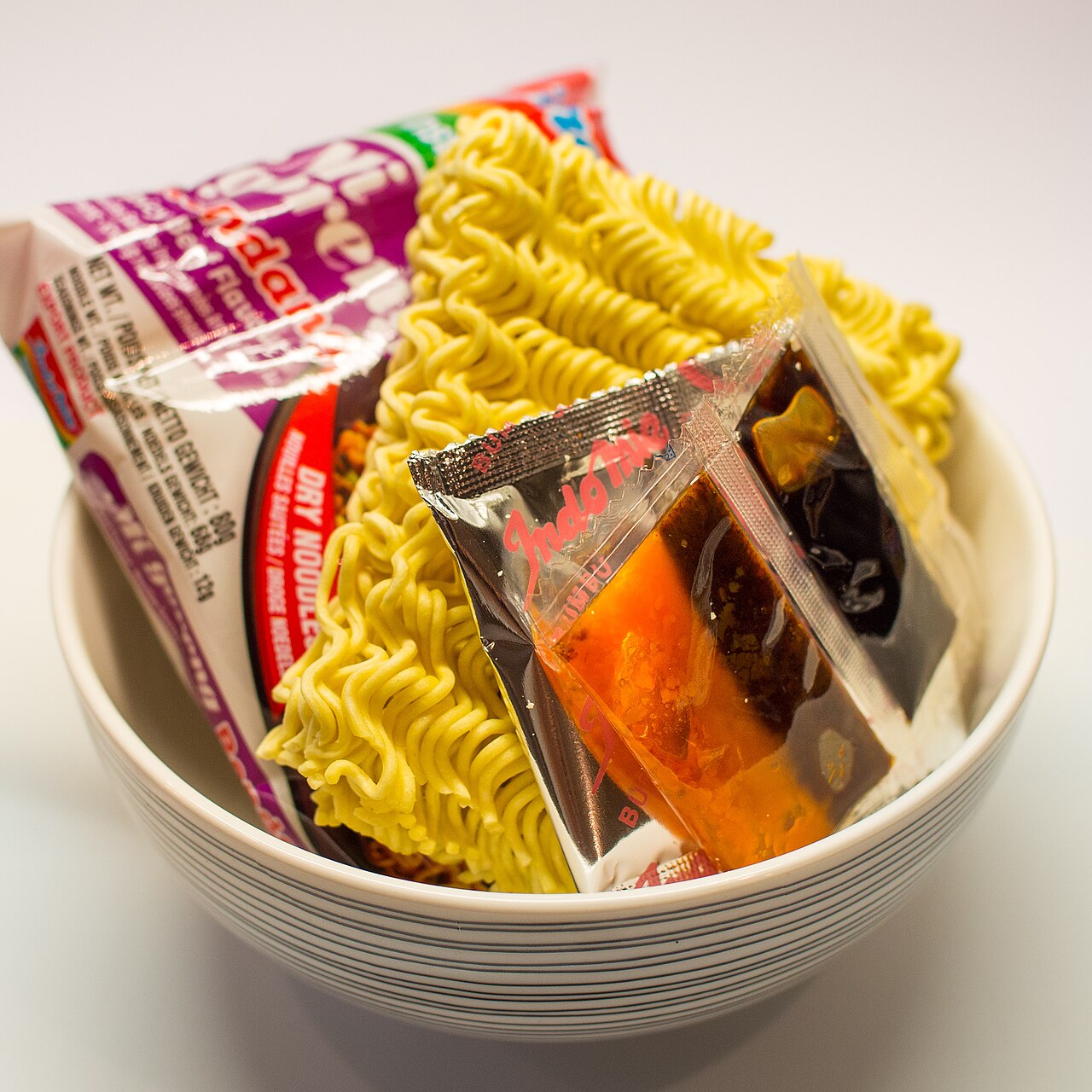 A bowl of Indomie Mi Goreng Rendang beside its opened sachets