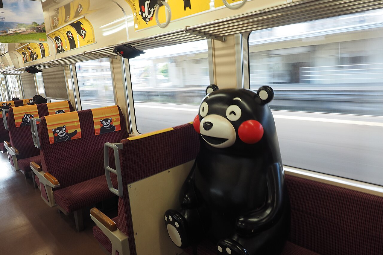 A large Kumamon figure seated on a Kumamoto-themed train