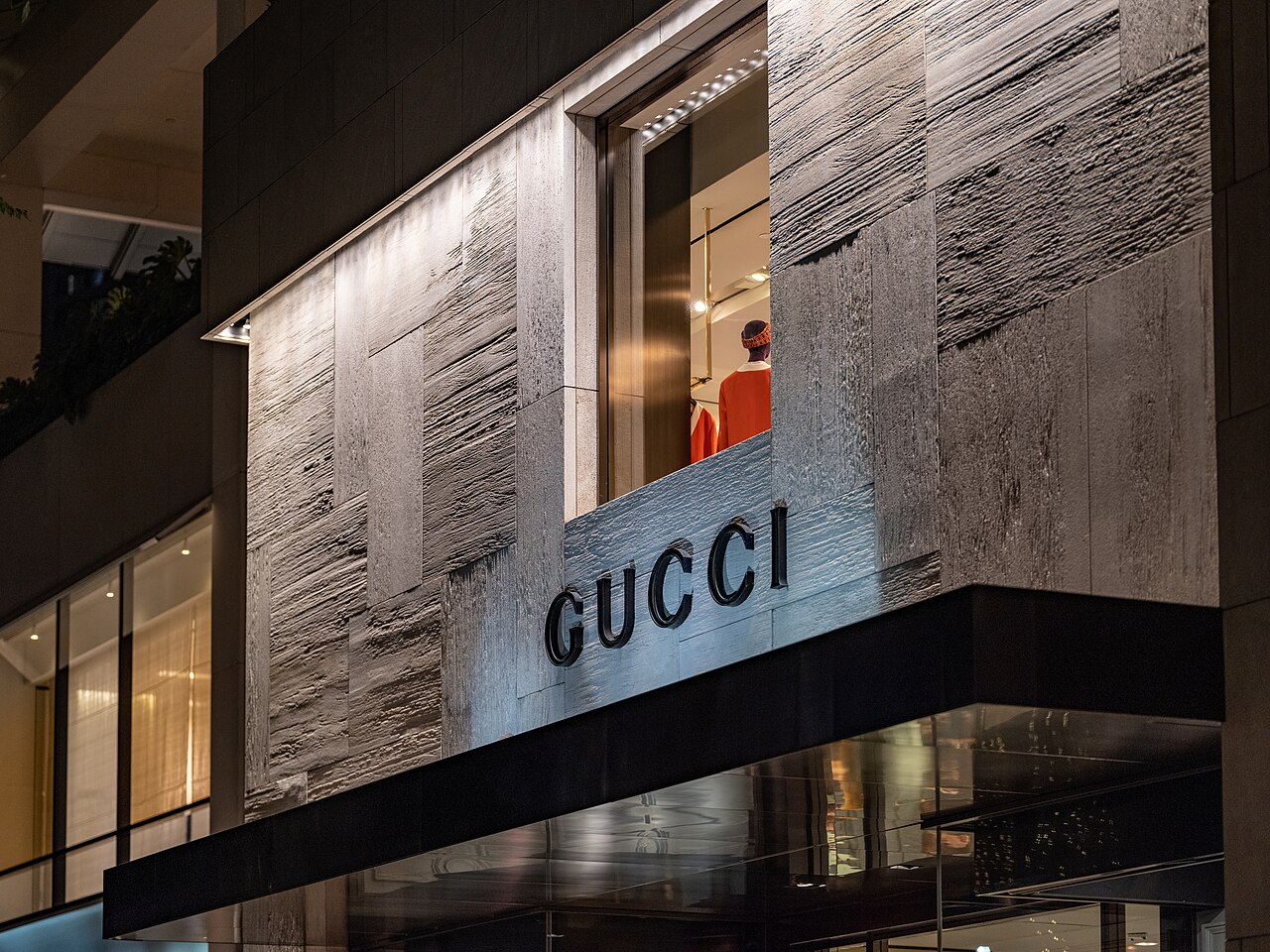 Gucci storefront at Luxury Row in Waikiki, Hawaii, with lettering on a textured stone facade.