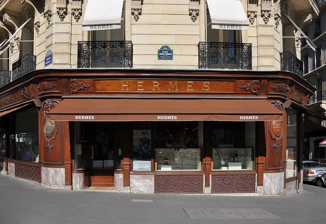 Hermès boutique on Avenue George V in Paris, with brown awnings and a wooden facade.