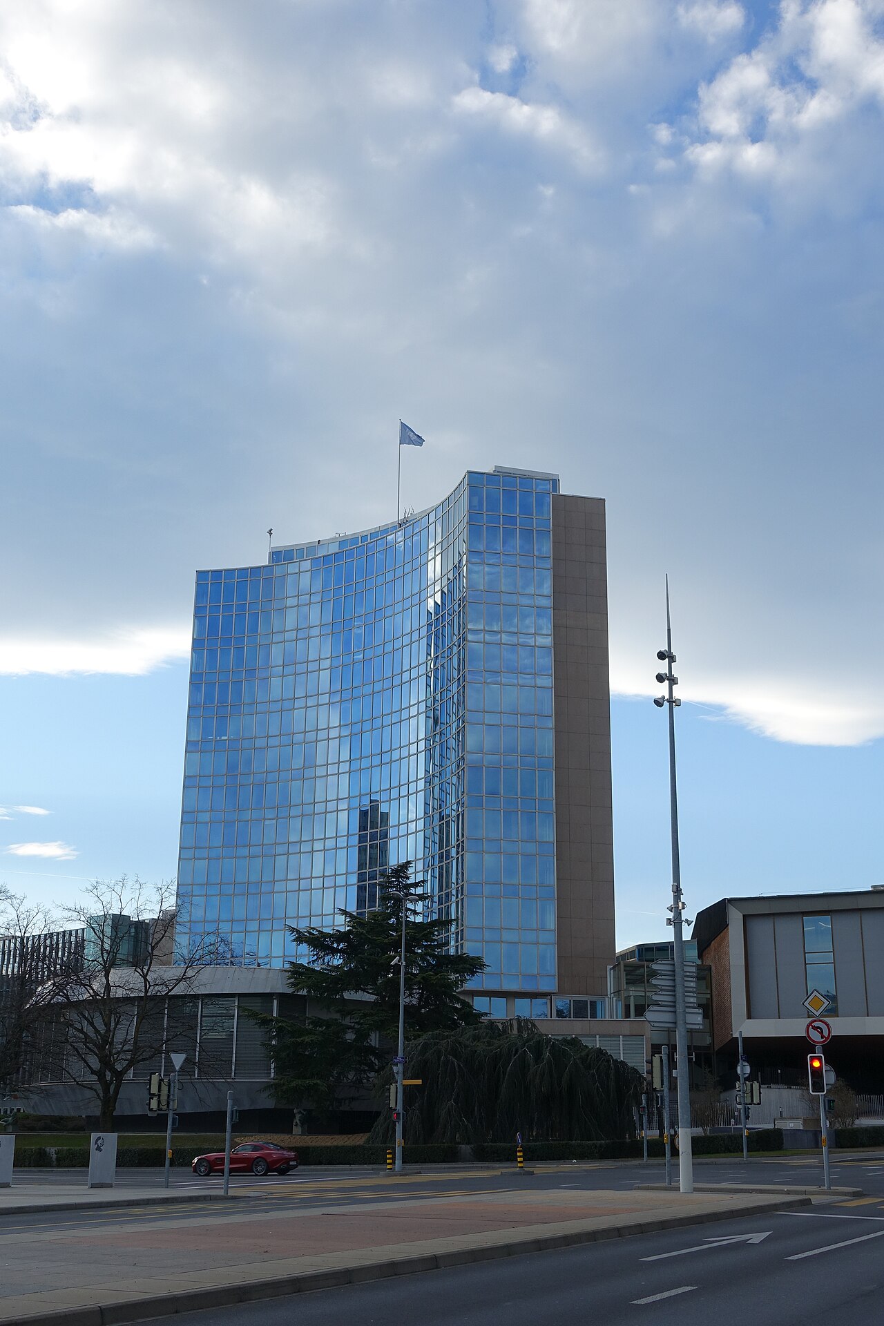 The glass-fronted WIPO main building in Geneva under a cloudy sky