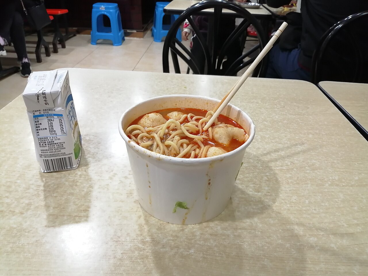 A carton of Yili milk beside a bowl of noodles